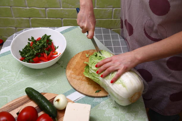 istock Woman cutting fresh beijing cabbage in kitchen 1906911329