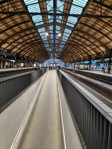 St. Gallen railway station main arrival and departure hall. The image shows the hall and platform without trains in the evening.