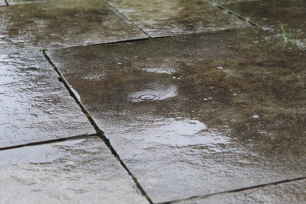 istock Rain water hitting concrete pavement outside with puddles 1906934654