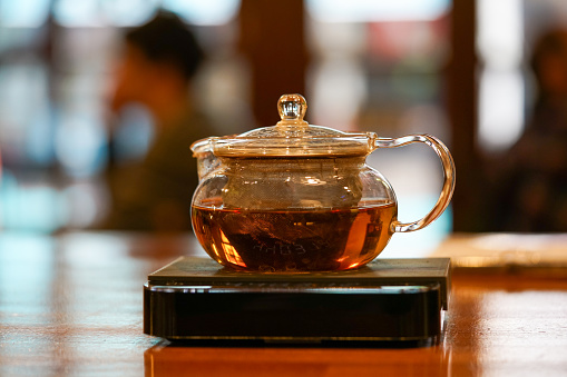 A person pouring a cup of tea from a teapot into a cup. A beautyful Asian teaset, hires photo