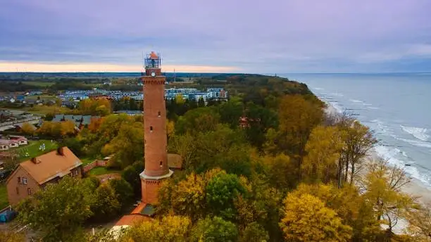 Drone-captured image of Gski Lighthouse, Poland, on a cloudy November day. The serene sea, gentle waves, and empty beach create a tranquil coastal scene, offering a peaceful retreat by the Baltic.
