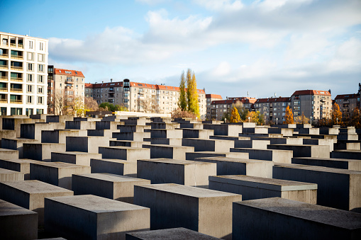 Berlin, Germany - 18. November 2022: The Holocaust memorial with residential buildings in the sunlight.