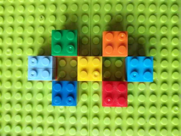 Plastic Colorful Construction and Building Blocks on Green Baseplate.