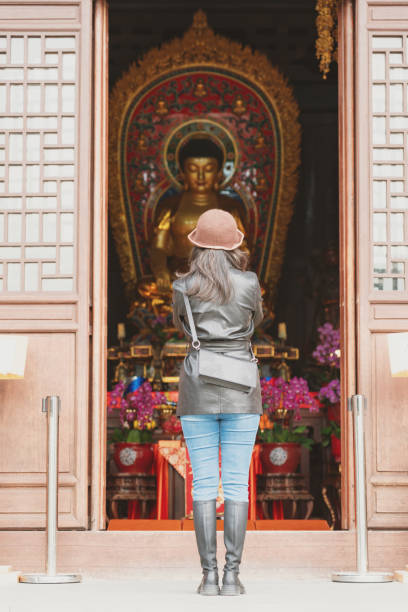 istock Asian lady praying in front of Buddha statue 1906971047