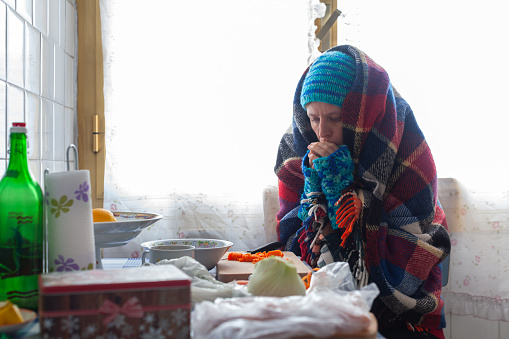 Mid Adult Woman Preparing herself a Poor Meal in an Old Cold Apartment - Poverty Social Issues