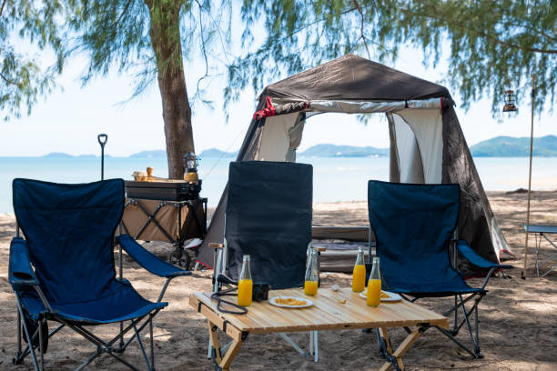 istock Unwind by the sea, Chairs, picnic table and tent create the perfect camping experience. Sunset, family, and the great outdoors this is where the journey to nature begins. The environment is calling. 1907002204