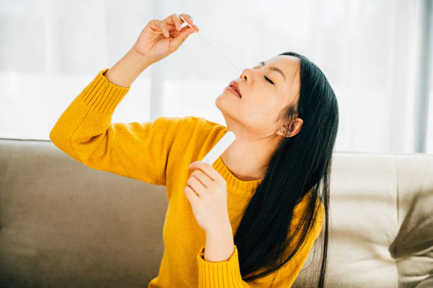 istock Woman at home uses a rapid antigen test kit inserting a swab into her nose 1907004493