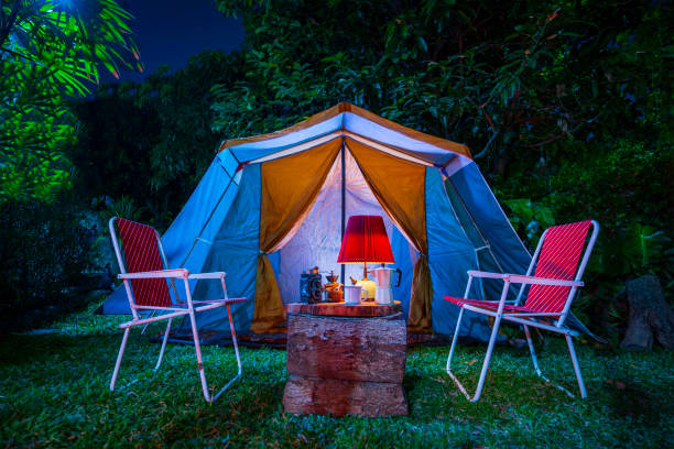 빈티지 캐빈 텐트, 앤티크 오일 램프, 복고풍 의자, 숲의 밤에 숲 캠핑 지역의 나무 테이블에 야외 커피 메이커가 있는 캠핑 텐��트 그룹 - lantern lamp hurricane old 뉴스 사진 이미지