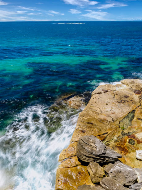 istock Powerful white swirling waves (blurred motion) crashing into rocky coastline 1907021662