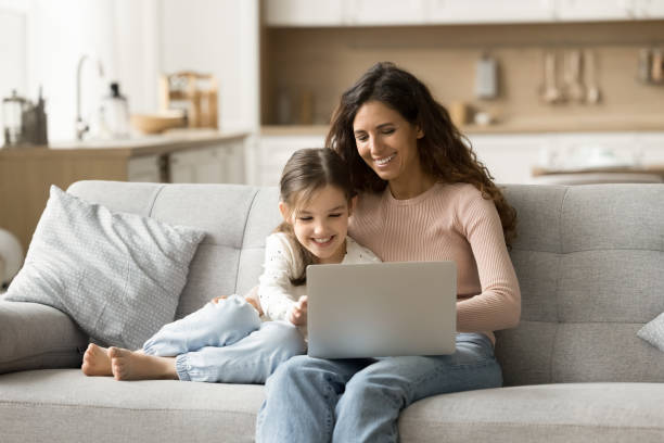 istock Cheerful brunette mom and cute kid girl using Internet service 1907023840