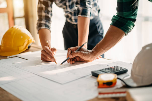 istock Two colleagues discussing data working and tablet, laptop with on on architectural project at construction site 1907033531