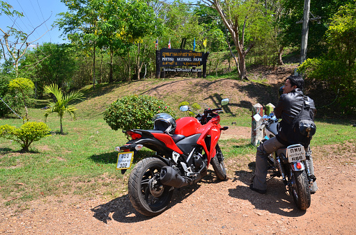 Thai man biker biking motorcycle travelers people riding motorbike travel visit Ban Taphoen Khi Village top of Khao Thewada mountain at Phu Toei National Park on May 14, 2011 in Suphanburi, Thailand