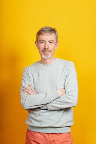 Studio portrait of a happy 50 year old man on a yellow background stock photo
