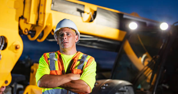 istock Construction worker standing by heavy machinery at night 1907136585
