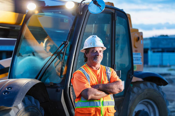 istock Worker standing in front of construction vehicle 1907137132