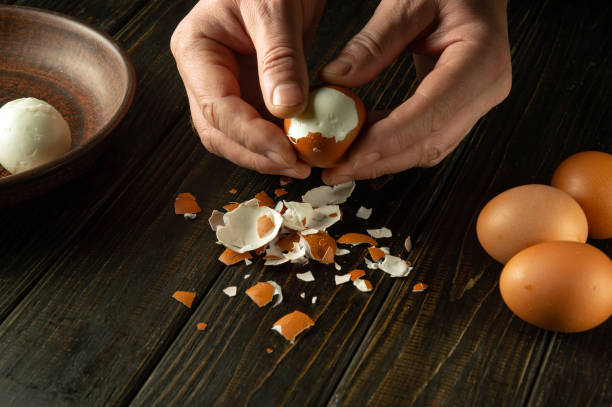 istock Close-up of a man hands peeling a boiled egg on a kitchen black table for a snack 1907139528