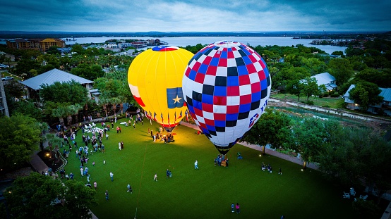 Horseshoe Bay, United States – April 08, 2023: An aerial view of brightly-colored hot air balloons in a park preparing to take off