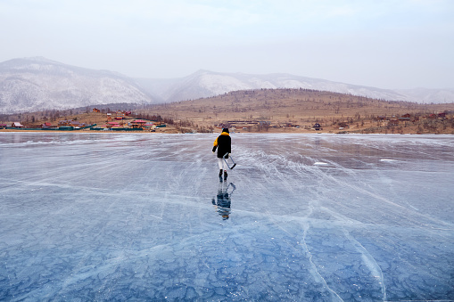 A young girl walks on the transparent ice of the frozen Lake Baikal. Active winter holidays.