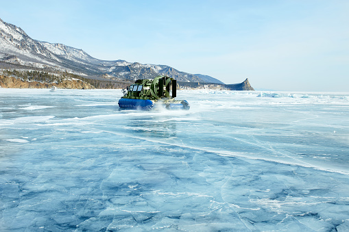 A hovercraft on the transparent ice of the frozen Lake Baikal. Winter trip.