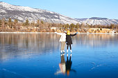 Mom and daughter are skating on the frozen Lake Baikal. Transparent ice. Winter travel