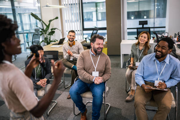 istock Young business woman lecturing her multiethnic colleagues. Having a speech while holding a microphone. 1907191435
