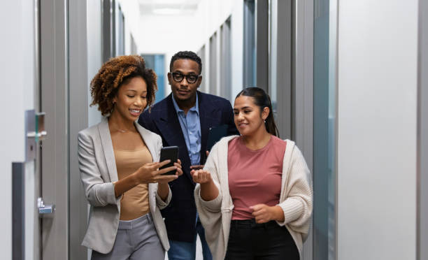 Multiracial office workers in hallway with mobile phone