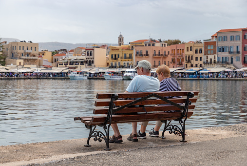 Chania, Crete, Greece - September 27, 2023: A picture of an elderly couple sitting on a bench in Chania.