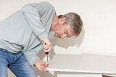 A 50-year-old man assembles flat-pack furniture