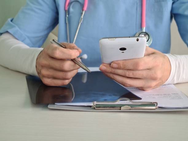 istock Doctor types text on smartphone screen in clinic 1907295966