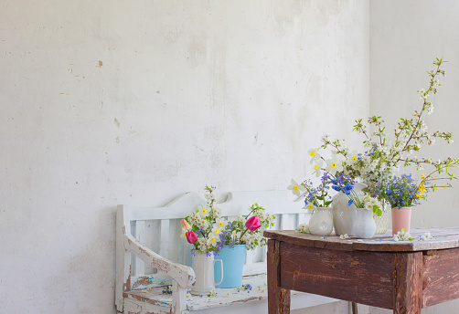 spring flowers in vintage white interior with old wooden bench
