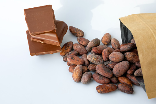 Cocoa beans. Milk chocolate. Package. White background. Sunny shadows.