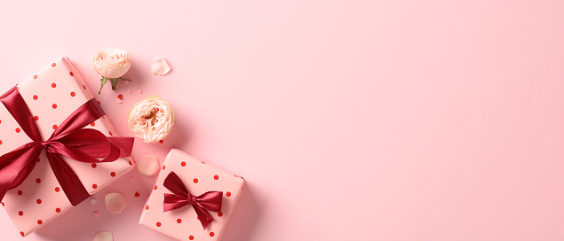 Valentine's day banner with gift boxes and flowers on pink table. Top view. Flat lay.