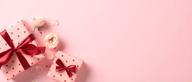 Valentine's day banner with gift boxes and flowers on pink table. Top view. Flat lay. stock photo