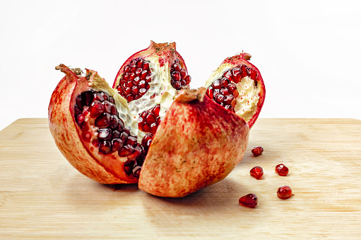 Cut pomegranate with ripe red juicy seeds on wooden board. Fruit for healthy eating.