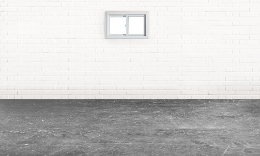 Empty basement room with a white brick wall cement flooring and a small window