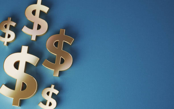 istock Yellow Metallic Dollar Sign Sitting on Blue Fabric Background 1907360459