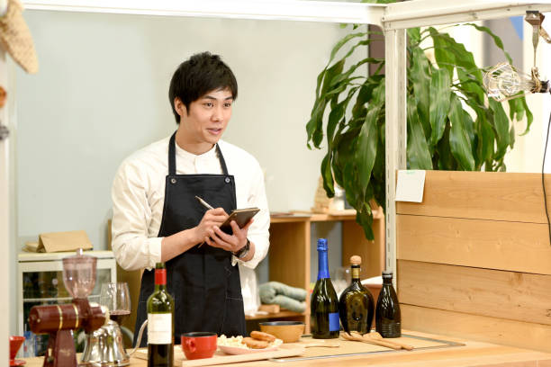 istock Young Asian male waitress smiling and checking orders at a restaurant 1907371031