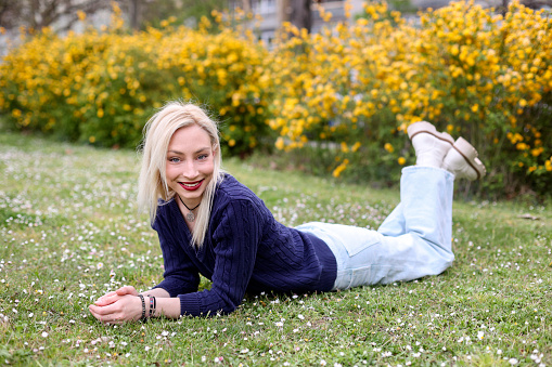 Young woman relaxing in a park. About 25 years old, Caucasian blonde.