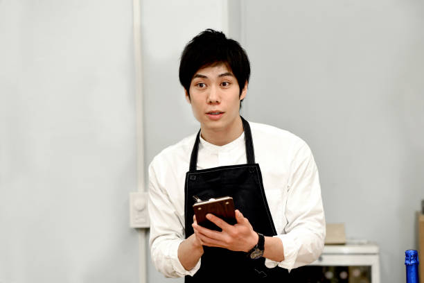 istock Young Asian male waitress smiling and checking orders at a restaurant 1907376311