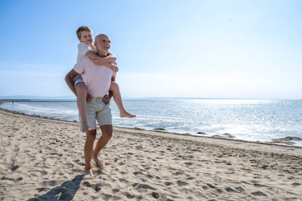 istock Man with his grandson walking on beach 1907376862