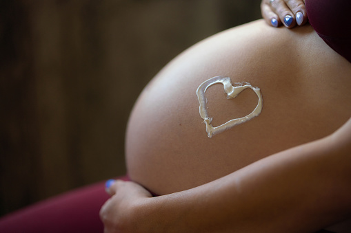 Close-up of a cream in the shape of a heart on a pregnant belly