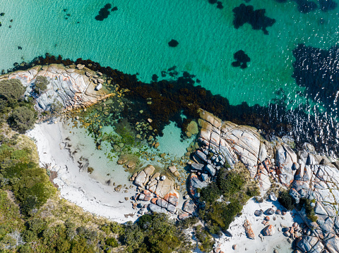 An aerial shot of a beautiful coast with turquoise waters and rocks