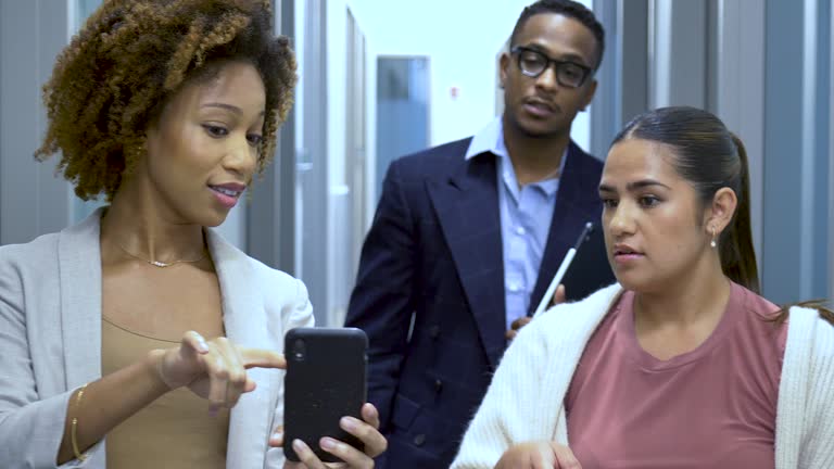 Multiracial office workers in hallway with mobile phone