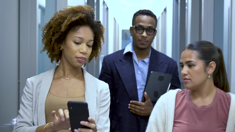 Multiracial office workers in hallway with mobile phone