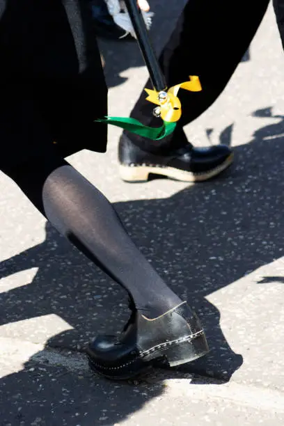 Photo of dancing feet in black shoes and clogs and black stockings on a tarmac pavement