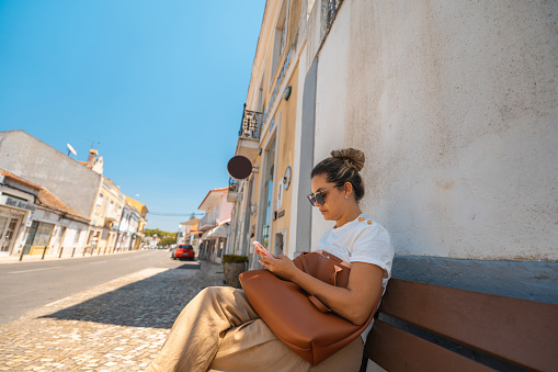 Woman sitting on a bench on the street in Vila Nogueira de Azeitão, Setúbal, Portugal