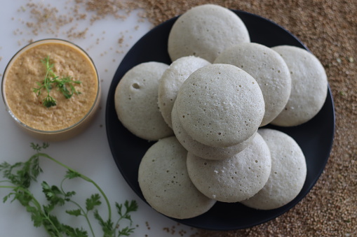 Kodo millet idly. Steamed savory cakes made of kodo millets and lentil flour, served with spiced coconut condiment