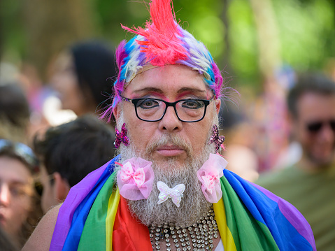 Vienna, Austria - June 17, 2023: People at Vienna Pride in summer on Wiener Ringstrasse, man with long grey beard, flag and colorful wig