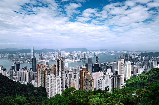 Aerial view of Hong Kong skyline and Victoria Harbor with cloudy blue sky in Hong Kong