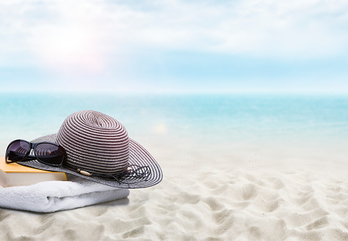 Book and sun hat on a sandy beach